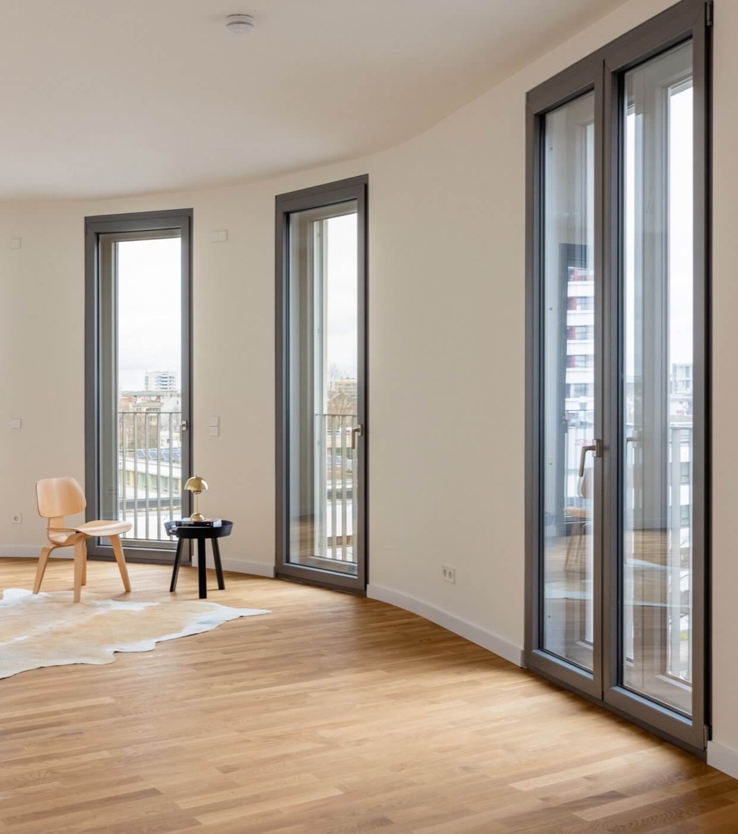 Helles Wohnzimmer mit Echtholzparkett und bodentiefen Fenstern